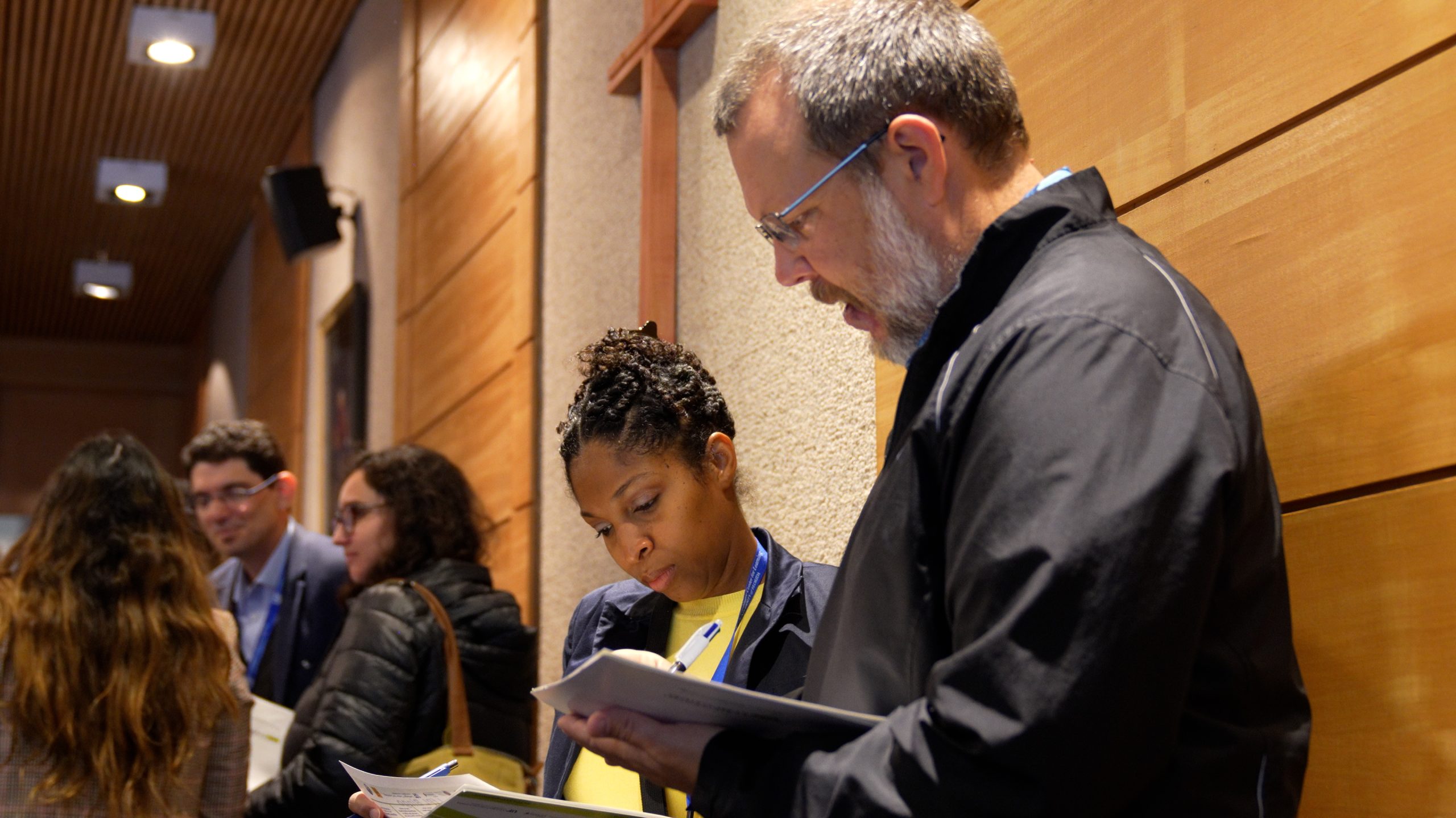 A group of participants at the 2024 Leadership for Professional Learning Symposium smiling and chatting in a lecture hall.
