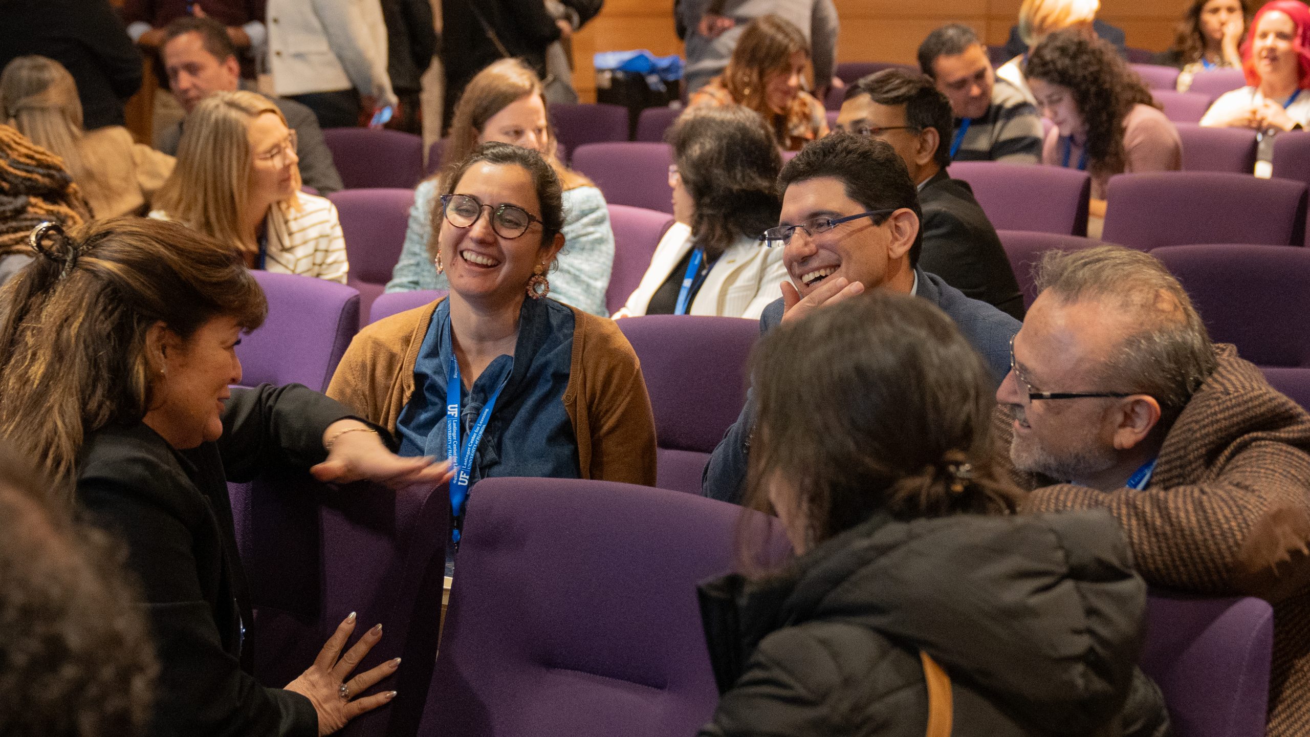 A group of participants at the 2024 Leadership for Professional Learning Symposium smiling and chatting in a lecture hall.