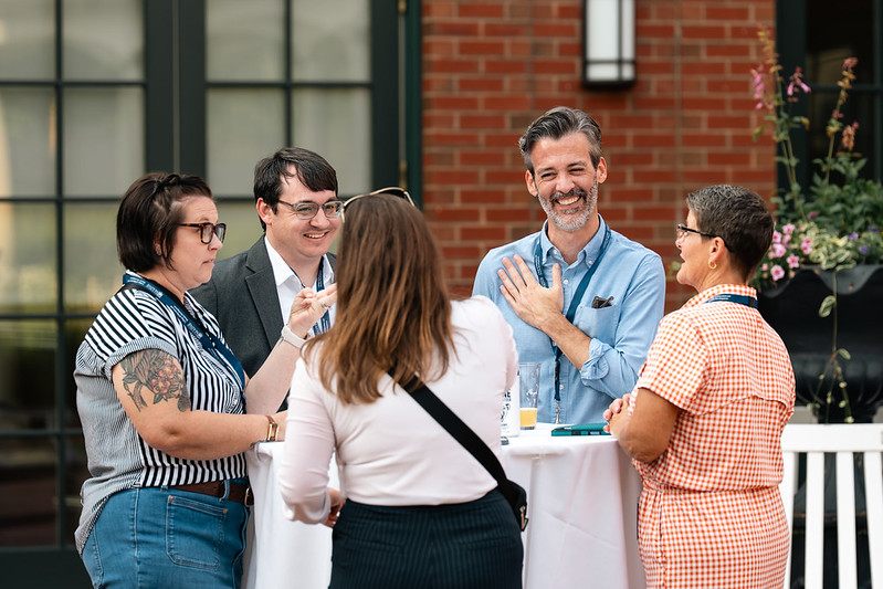 A group of five people having a discussion at an outdoor table