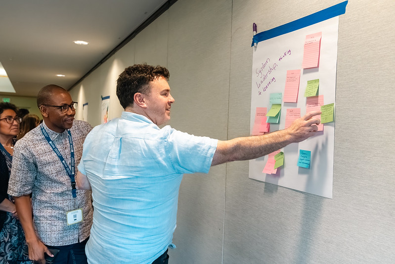 Two men placing sticky notes on a sheet during an LfPL workshop