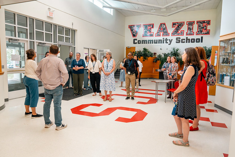 A group of participants at the 2024 Leadership for Professional Learning Symposium smiling and chatting in a lecture hall.